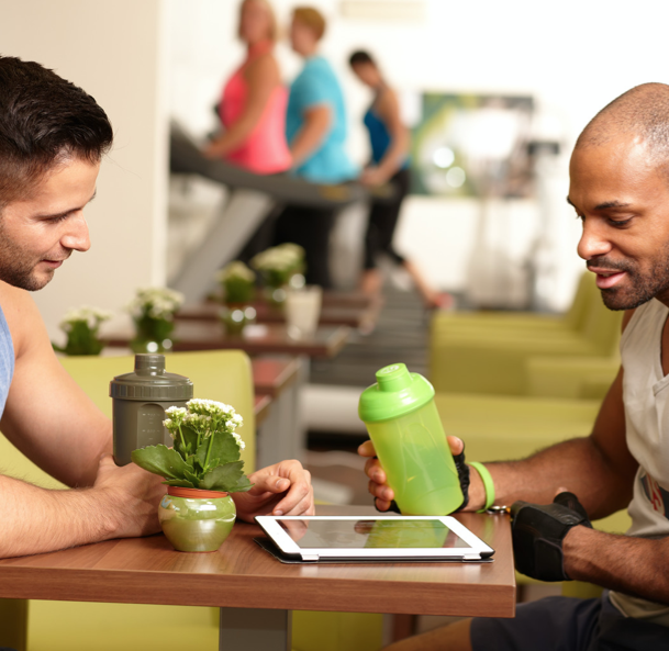 two men talking at gym with green smoothies