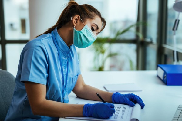 Female scientist doing on medical research and writing data while working during virus epidemic in a hospital