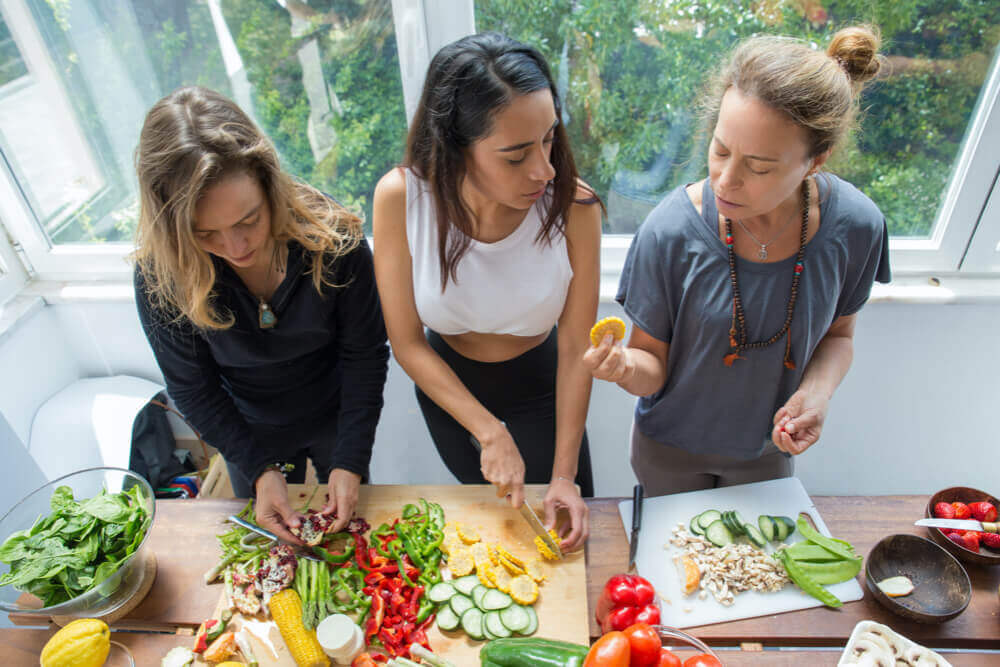 beautiful women cutting up vegetables preparing a vegan meal