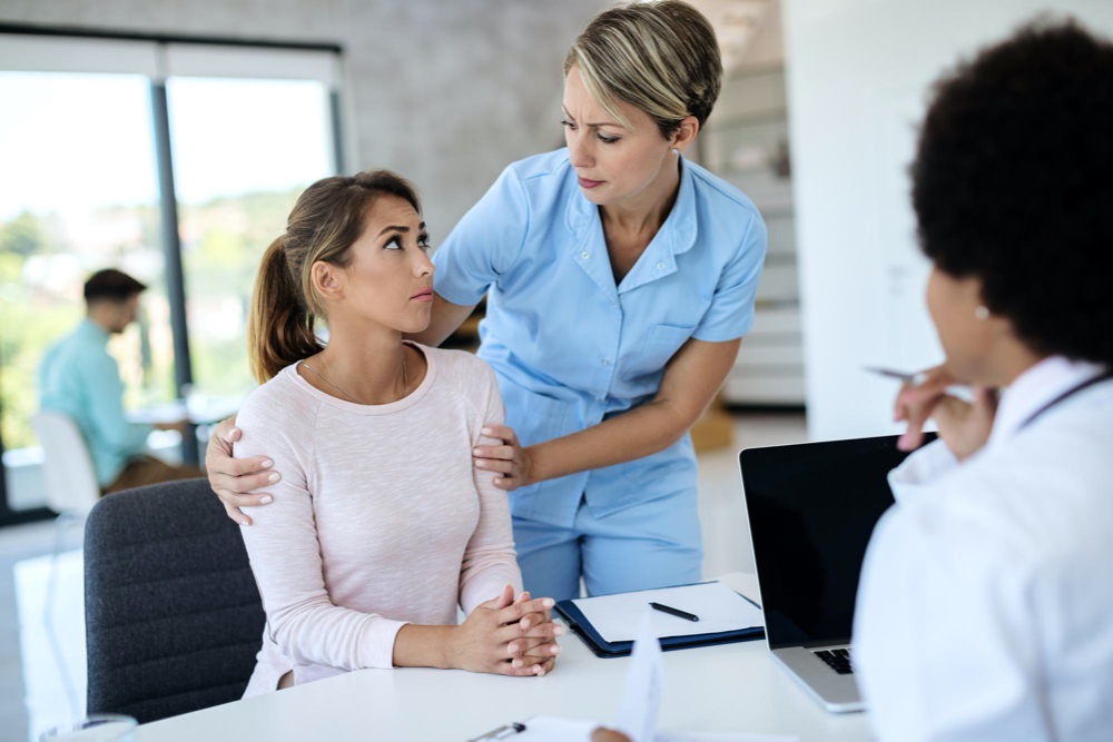 doctor comforting young woman at lab about her health