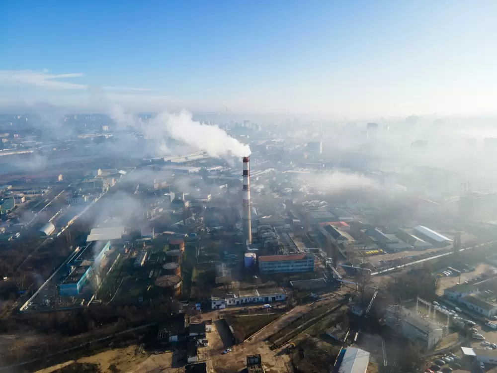 Aerial drone view of chisinau. thermal station with smoke coming out of the tube. buildings and roads. fog in the air.