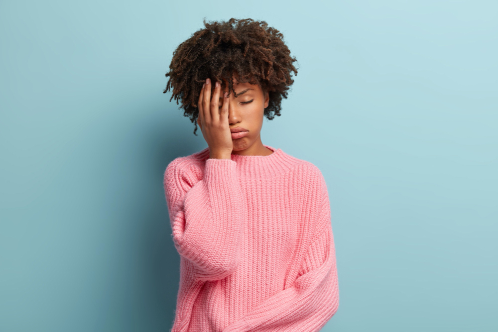 beautiful-overworked-woman-feels-sleepy-covers-half-face-with-palm-keeps-eyes-closed