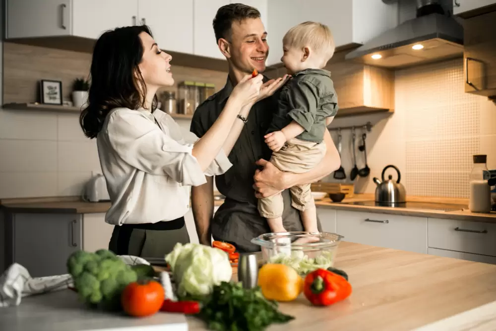 Happy family in the kitchen with vegetables and fruit on the kitchen table.