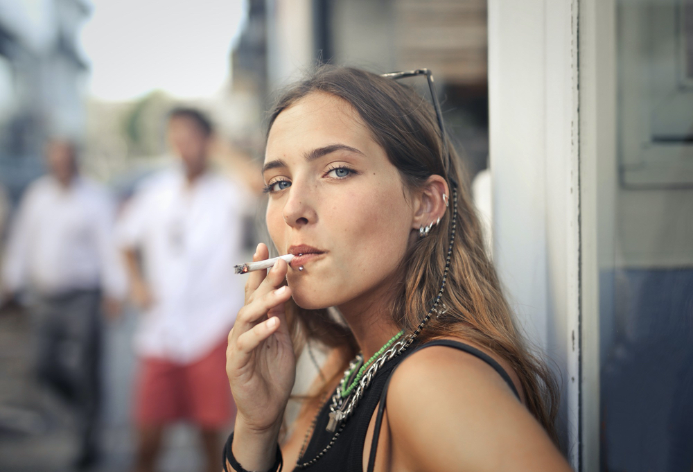 photo portrait of a young female smoking in the street