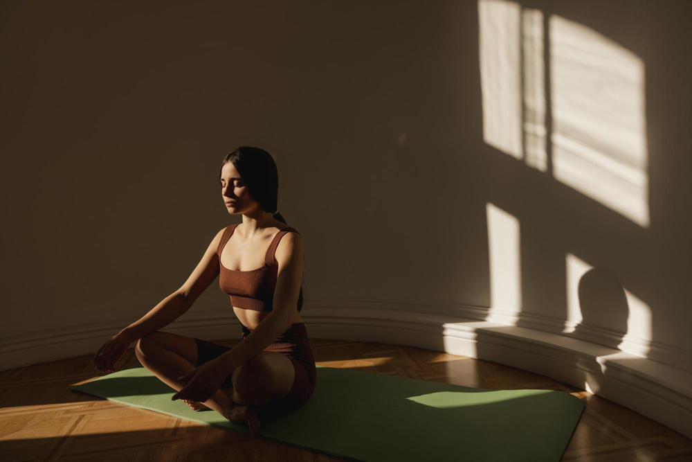 cute woman sitting on yoga mat meditating in a dark room