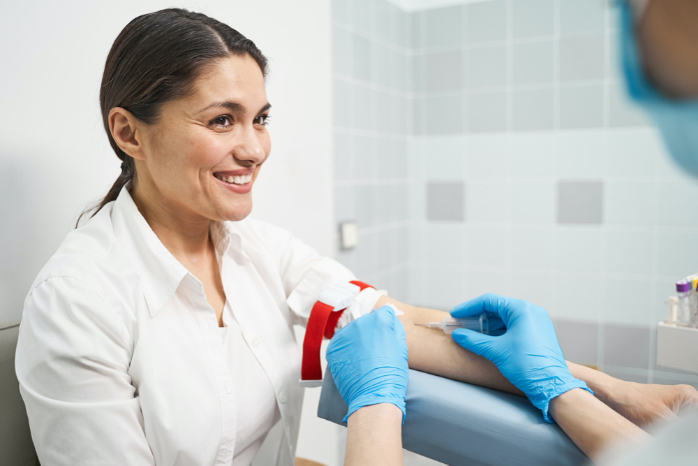 positive. kind young patient keeping smile on her face while making fist during sampling her blood