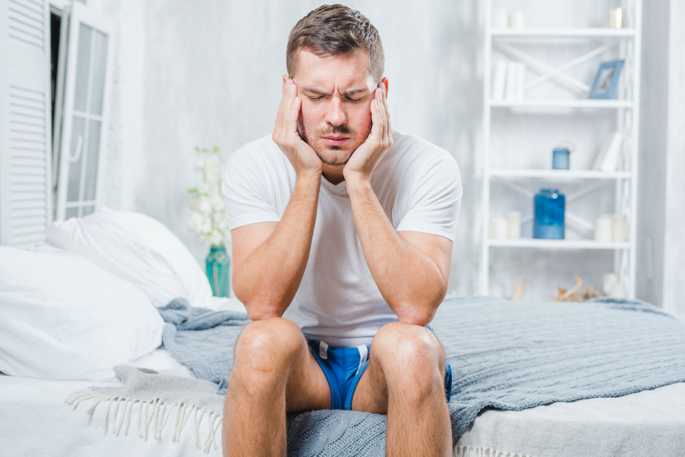 photo close-up of a man sitting on bed having headache