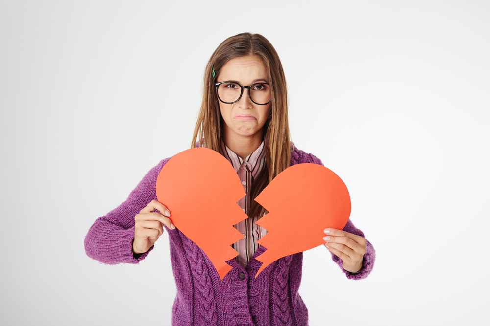 Free photo close up portrait of young woman holding a broken heart shape
