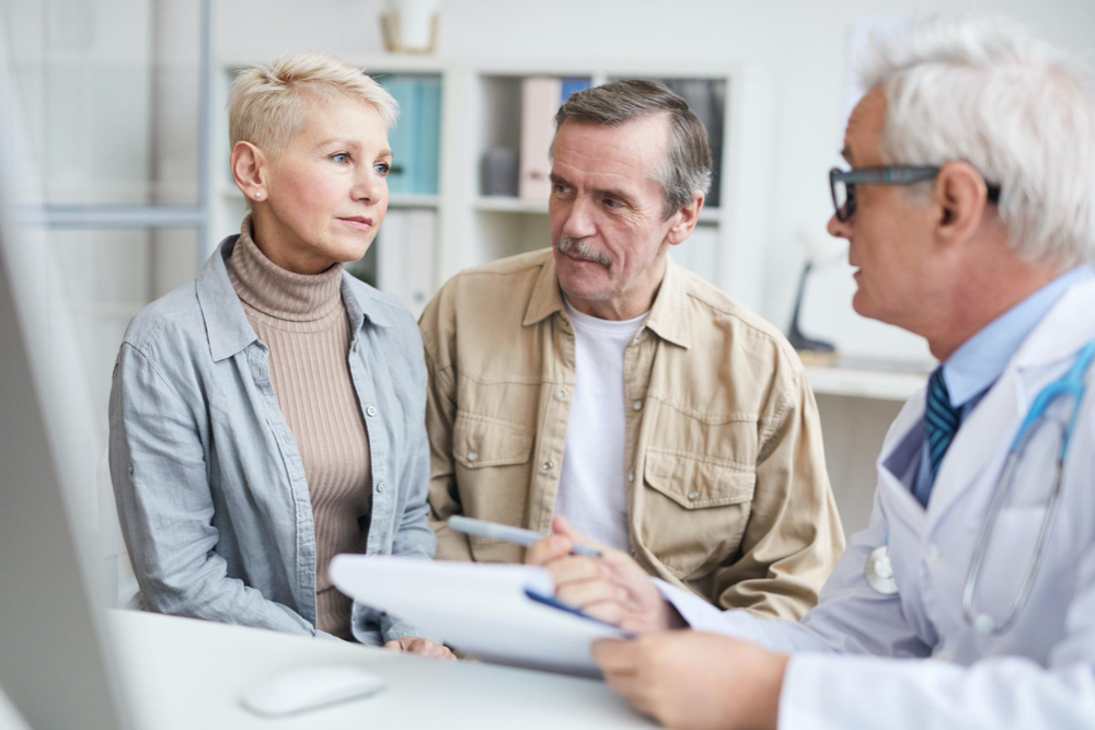 Photo doctor talking to senior couple in own office
