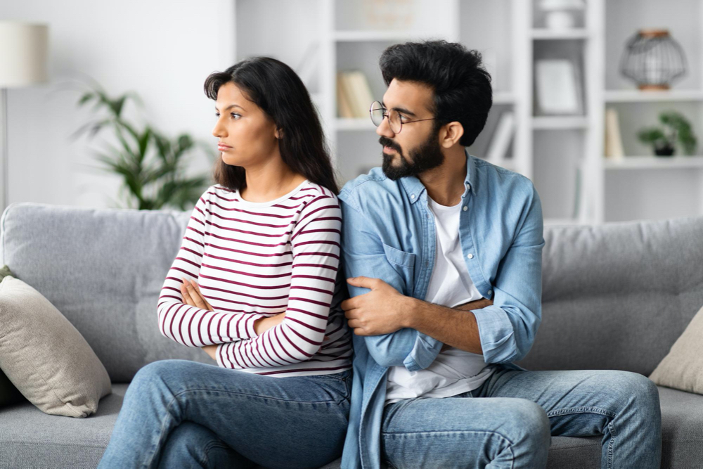 young indian man looking at his offended girlfriend or wife