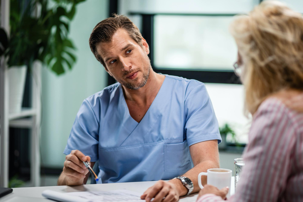 General practitioner communicating with a woman during the appointment at doctor's office
