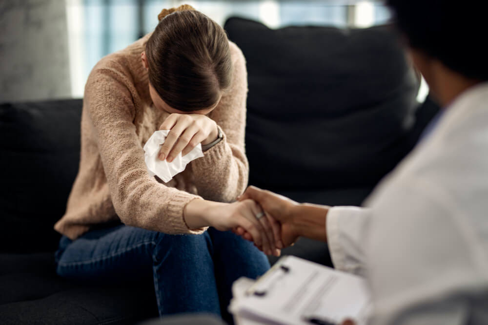 Caring African American woman consoling sad woman before group therapy meeting