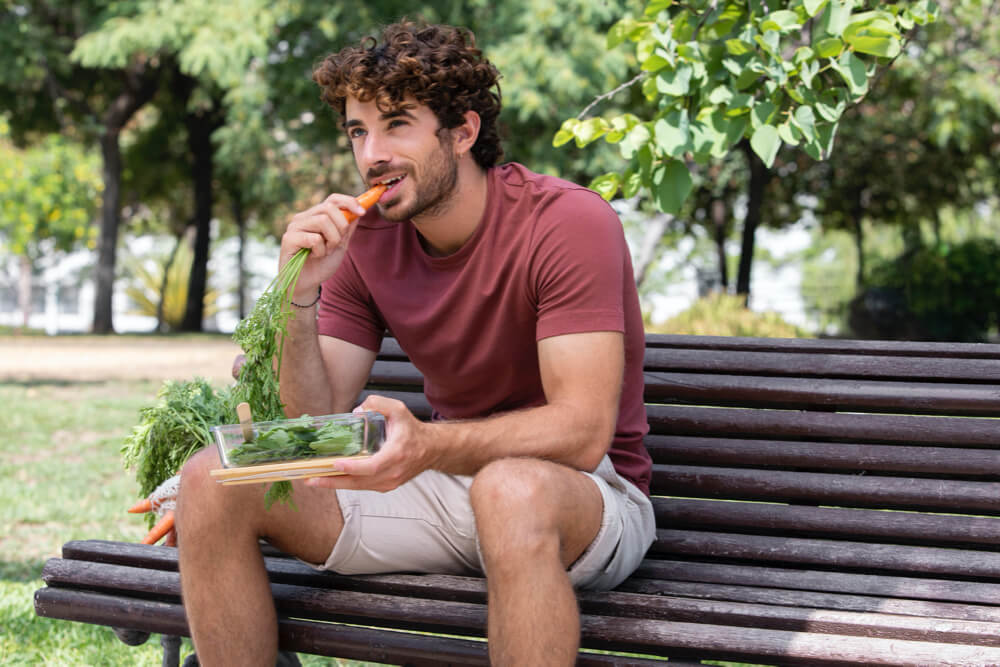 Close up on handsome man eating in park